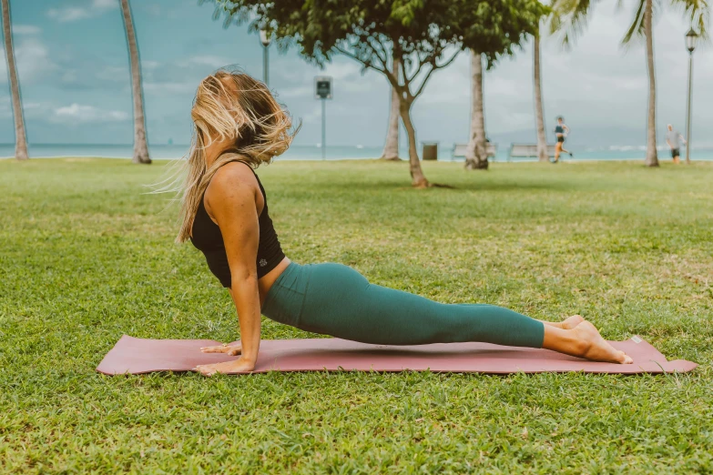 a woman doing a yoga pose on a pink yoga mat, by Nina Hamnett, unsplash, on a green lawn, sub tropical, back arched, manuka