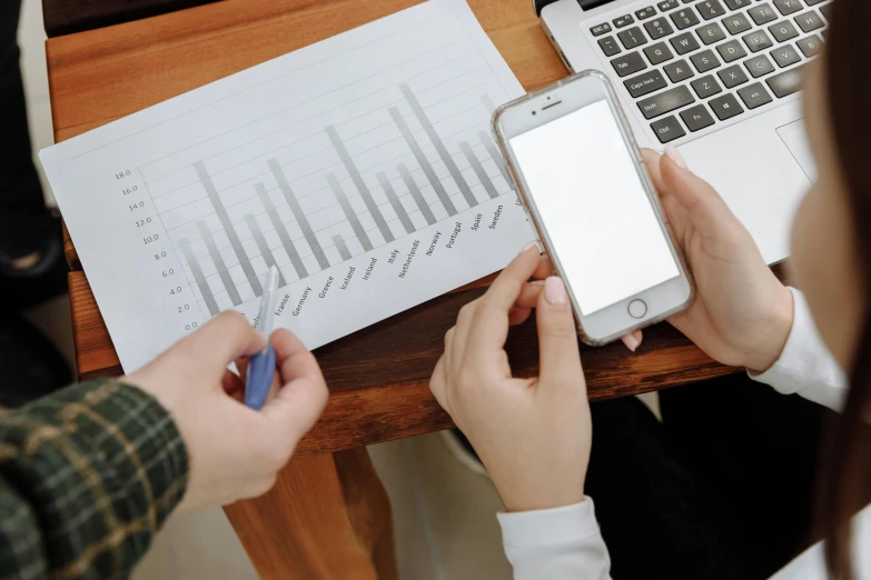 a person sitting at a table with a laptop and a cell phone, trending on pexels, analytical art, informative graphs and diagrams, avatar image, a wooden, document photo