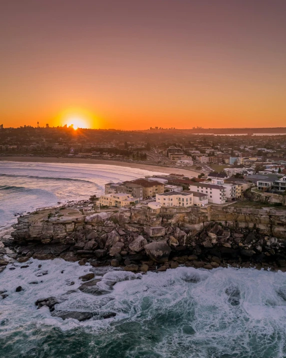 a large body of water next to a beach, a matte painting, pexels contest winner, happening, bondi beach in the background, sun down, aerial view of a city, winter sun