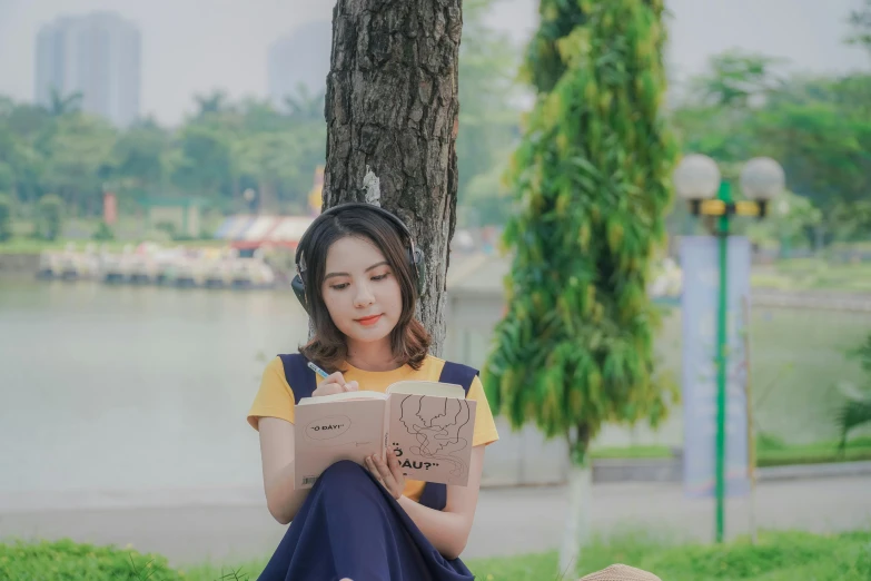 a woman sitting under a tree reading a book, inspired by Ruth Jên, pexels contest winner, realism, anime thai girl, background image, casually dressed, yellow