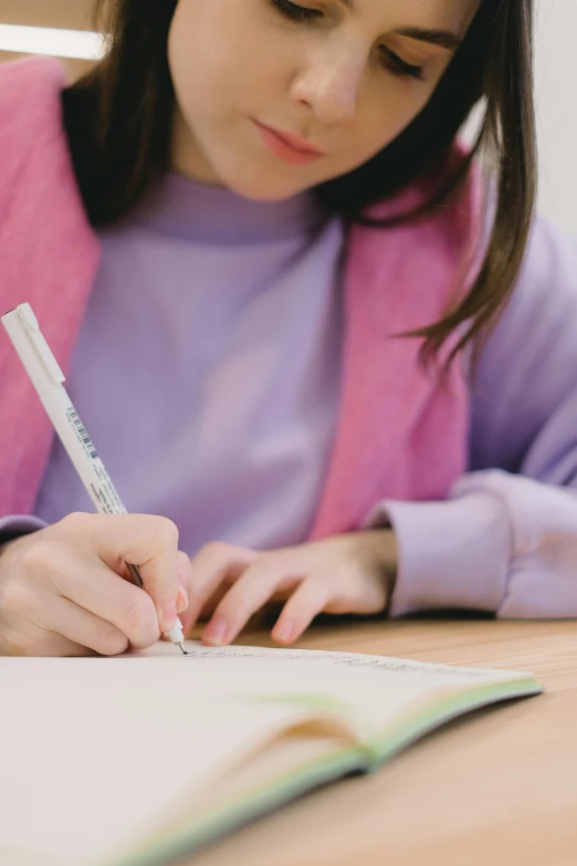 a woman sitting at a table writing on a piece of paper, a child's drawing, pexels, academic art, purple, katherine lam, multiple stories, teenage female schoolgirl