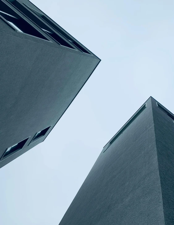 a couple of tall buildings sitting next to each other, an album cover, unsplash contest winner, brutalism, trending on vsco, ignant, gray concrete, looking upward