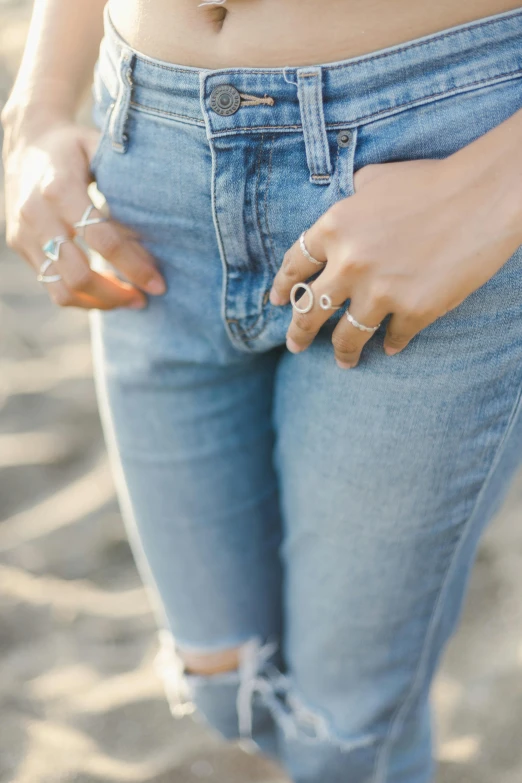 a woman standing on top of a sandy beach, inspired by L. A. Ring, happening, silver details, wearing denim, circles, zoomed in