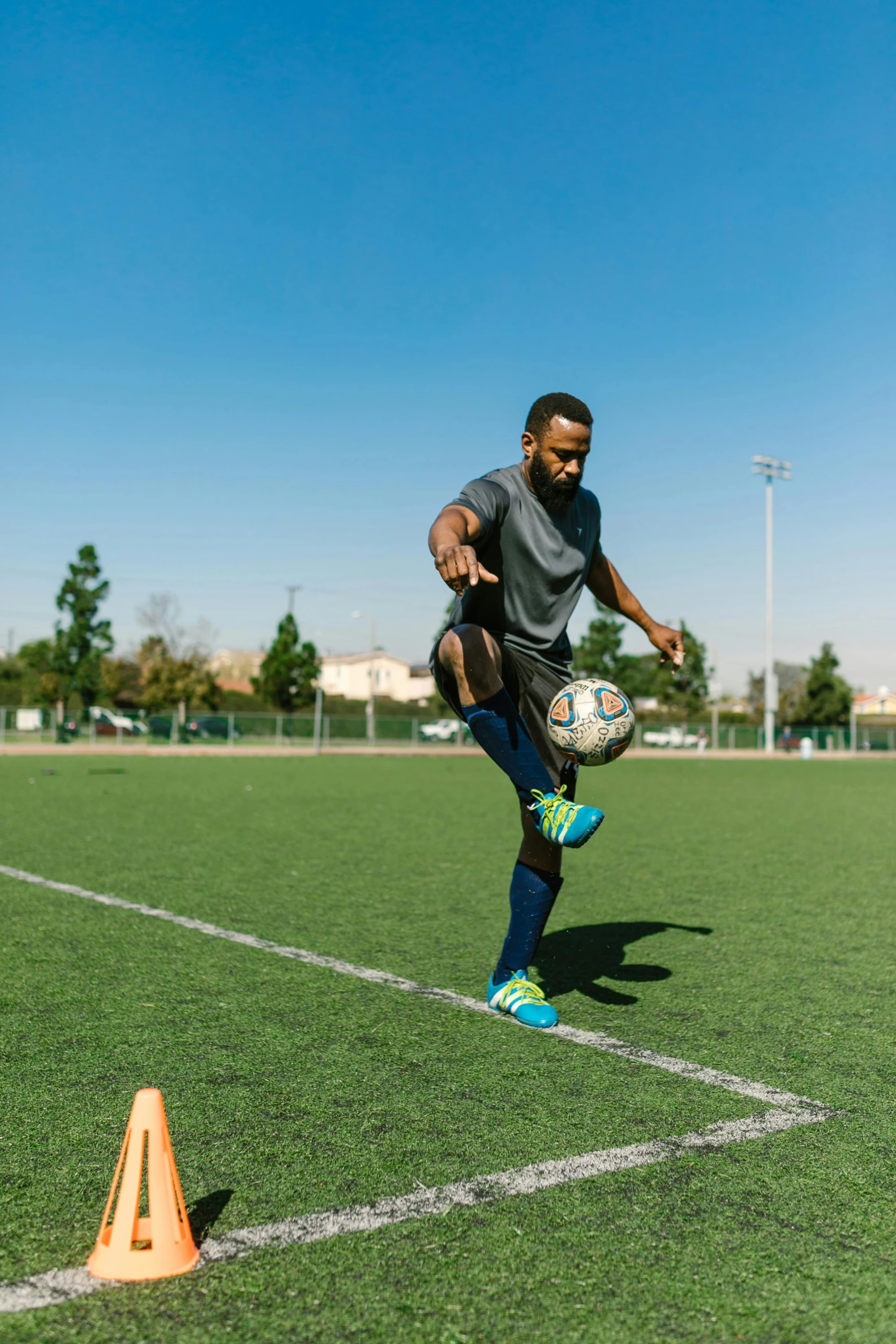 a man kicking a soccer ball on a field, bay area, teaching, square, kano)