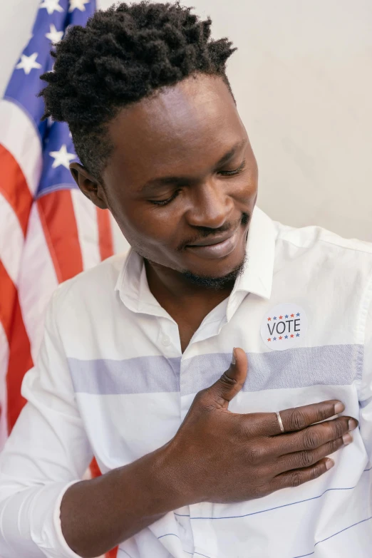 a man standing in front of an american flag, emmanuel shiru, heart emblem on chest, hand on cheek, contest winner 2021