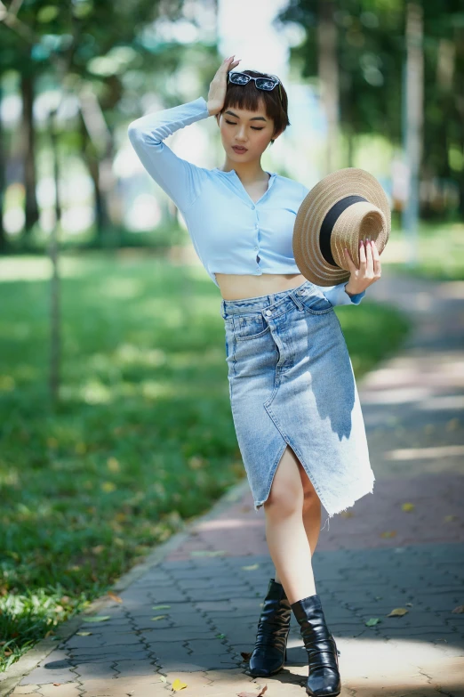 a woman walking down a sidewalk with a hat on her head, by Tan Ting-pho, pexels contest winner, mini jeans skirt, attractive pose, square, light blue