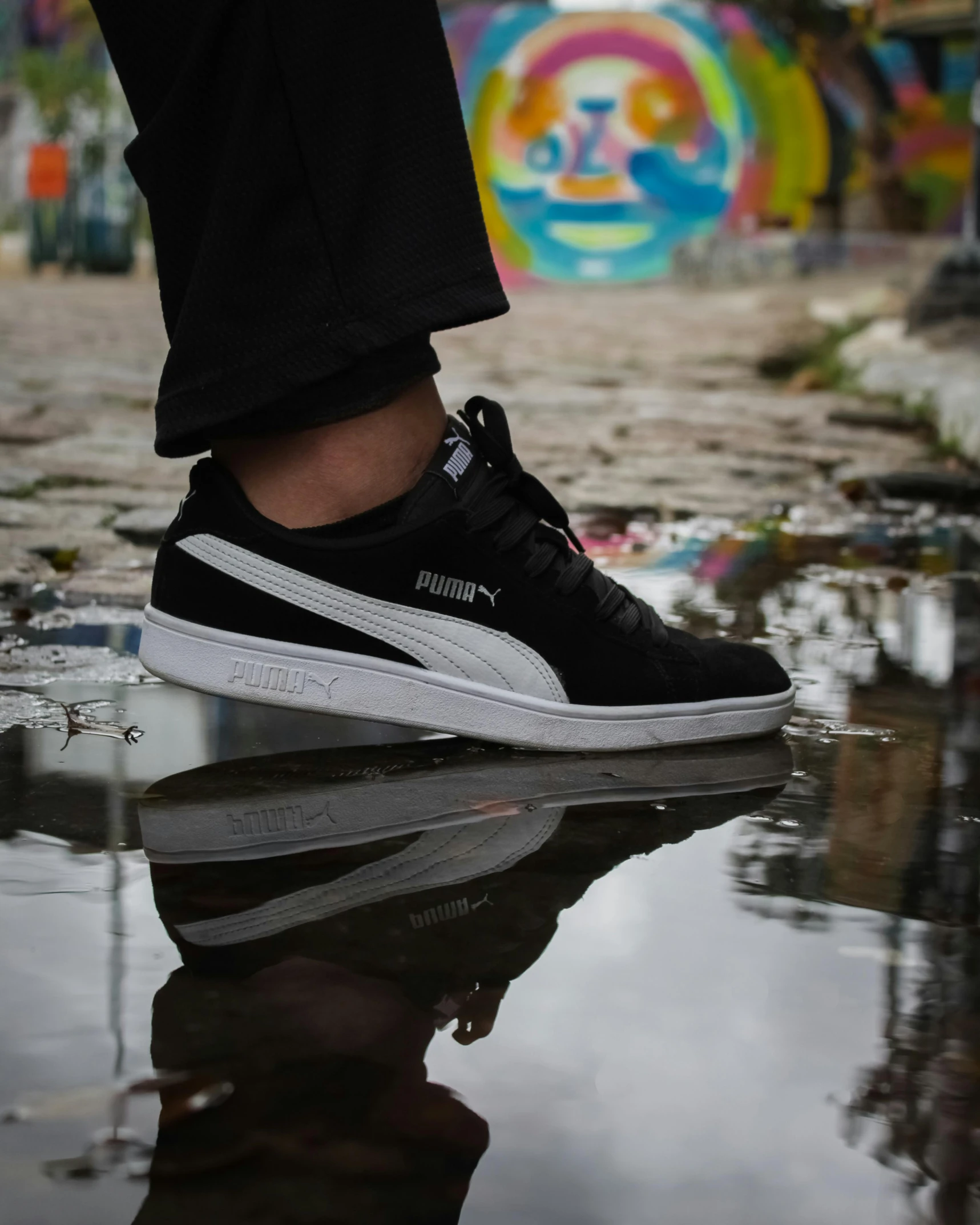 a person standing on top of a puddle of water, by Julia Pishtar, pexels contest winner, graffiti, based on a puma, white and black, gum rubber outsole, looking to his side