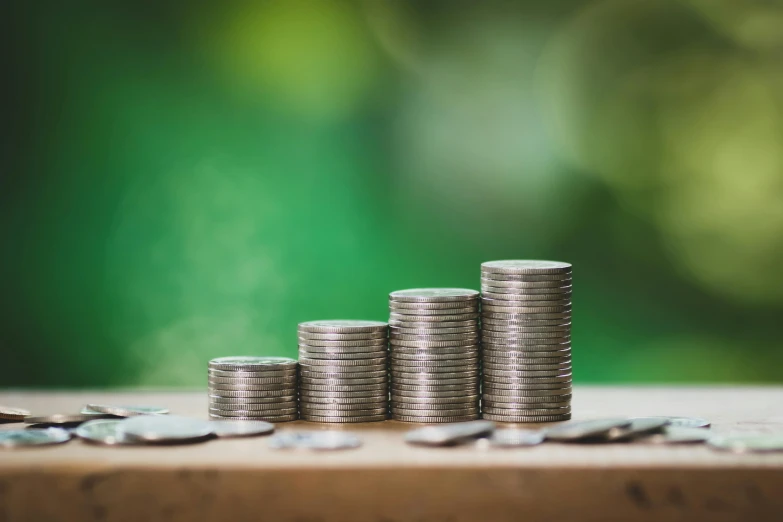 a stack of coins sitting on top of a wooden table, a green, digital image, thumbnail, stacked image