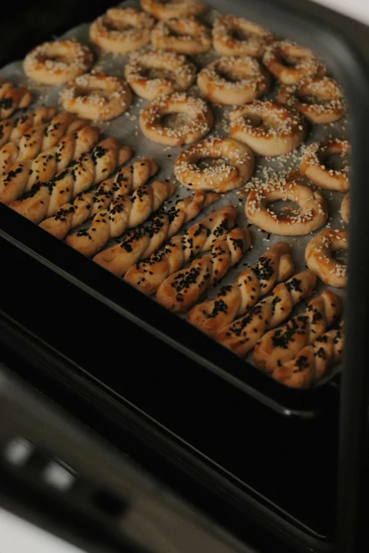 a pan filled with pretzels sitting on top of a stove, bagels, alessio albi, premium quality, baking cookies