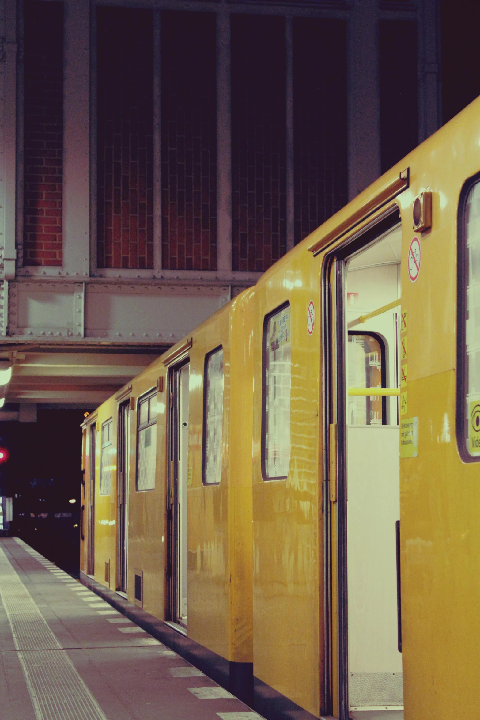 a yellow train pulling into a train station, by Kristian Zahrtmann, unsplash, berlin 1 9 8 2, square, nightlife, doors