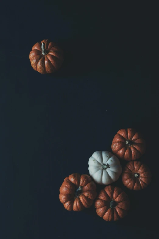 a group of small pumpkins sitting on top of a table, by Carey Morris, unsplash contest winner, minimalism, on black paper, bay area, reds, ☁🌪🌙👩🏾