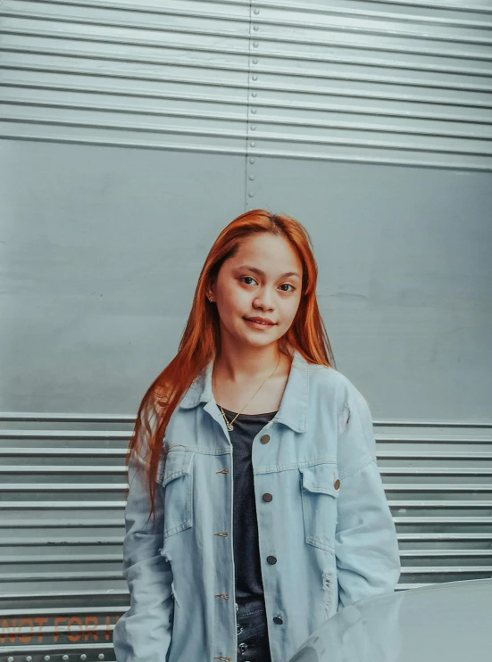 a woman standing in front of a metal wall, pexels contest winner, realism, portrait of a red haired girl, joy ang, asher duran, low quality photo