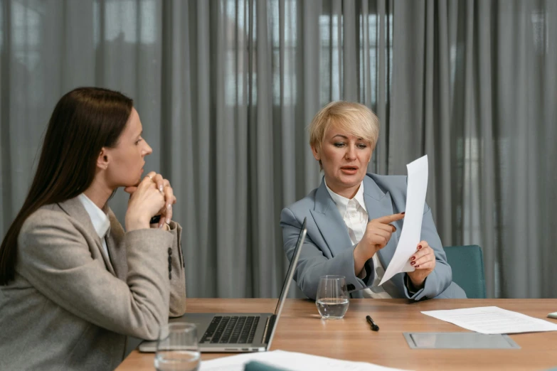 two women sitting at a table with papers in front of them, pexels contest winner, female in office dress, paul barson, in a meeting room, te pae