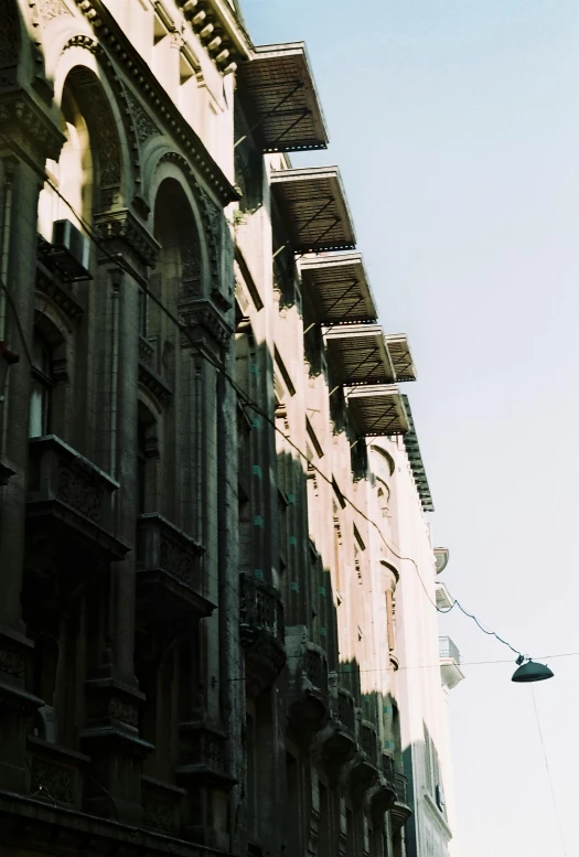 a group of people walking down a street next to tall buildings, a photo, inspired by Gianfredo Camesi, renaissance, awnings, light above palace, sunfaded, wrought iron architecture