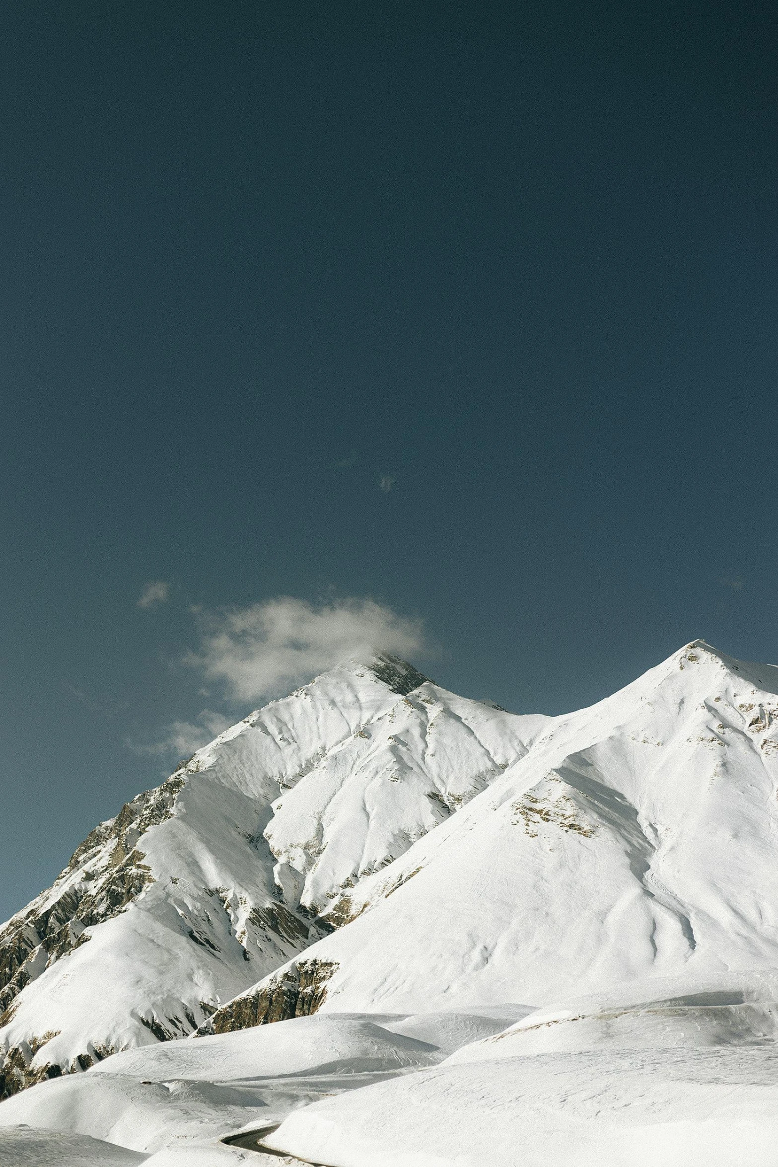 a man riding skis down a snow covered slope, an album cover, trending on unsplash, minimalism, himalayas, big moon on the right, distant photo, view from below