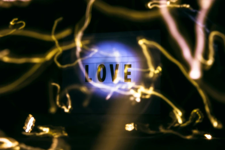a blurry picture of the word love, by Daniel Lieske, trending on pexels, light and space, large electrical gold sparks, love craftian, consciousness projection, blue and yellow lighting