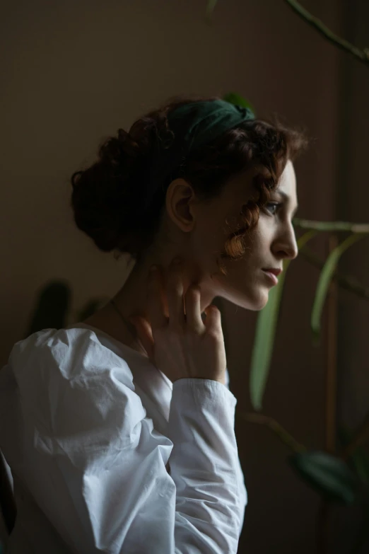 a woman in a white shirt looking out a window, a character portrait, inspired by Anna Füssli, trending on pexels, renaissance, with ivy, profile image, gentle lighting, thoughtful pose