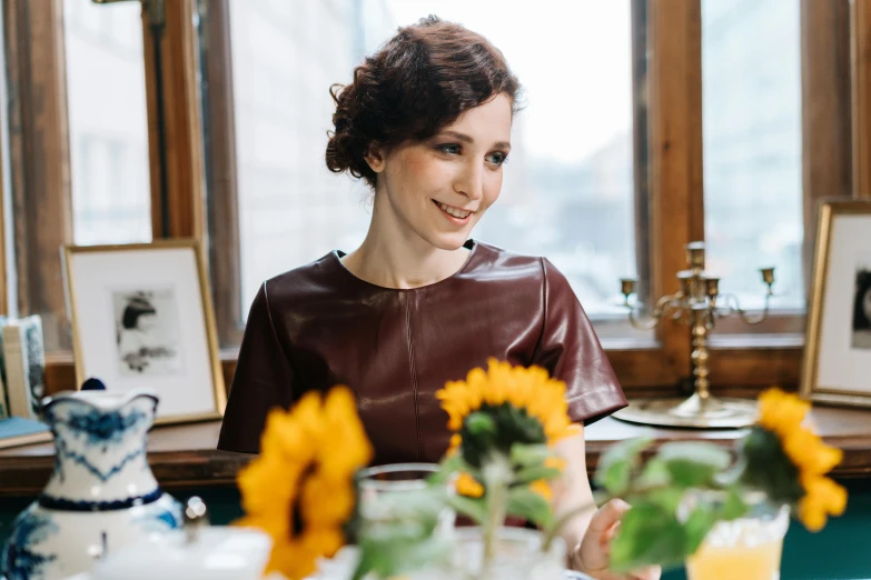 a woman sitting at a table with a vase of flowers, beautiful caitriona balfe, avatar image, jovana rikalo, smiling and looking directly