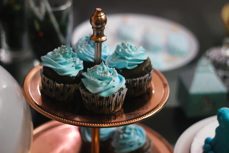 a table topped with cupcakes covered in blue frosting, pexels, silver, thumbnail, dessert, chocolate