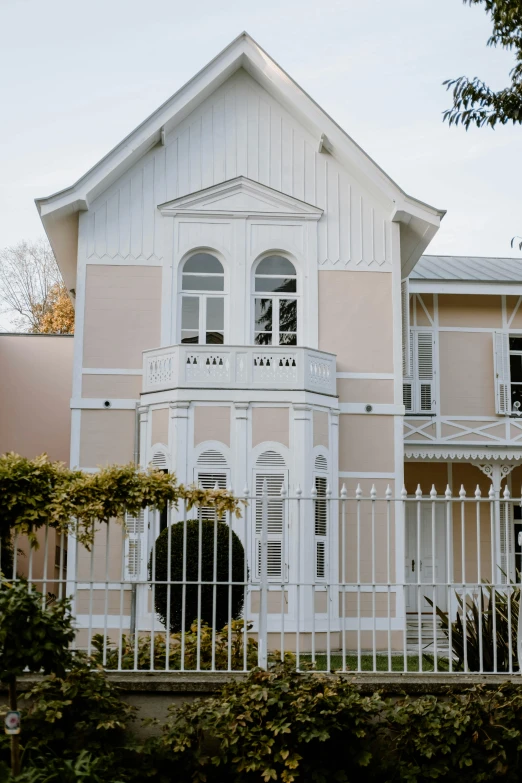 a house with a fence in front of it, inspired by Edwin Deakin, unsplash, heidelberg school, exterior view, pale colors, new zealand, 3/4 front view