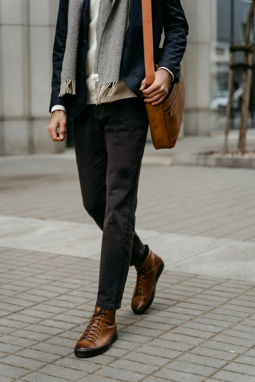 a man walking down a sidewalk next to a building, trending on pexels, renaissance, brown pants, black leather accents, detailed product shot, full body image