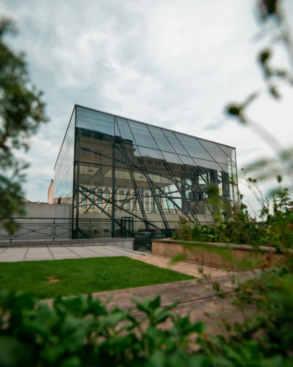 a large glass building sitting on top of a lush green field, by Emma Andijewska, unsplash, bauhaus, roof garden, museum quality photo, multiple stories, 3/4 front view