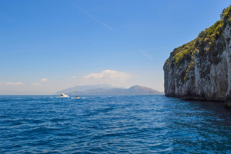 a boat in the middle of a body of water, by Giuseppe Avanzi, pexels contest winner, capri coast, clear blue skies, skull island, thumbnail