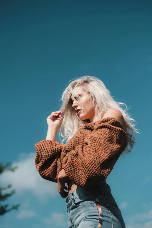 a woman standing in front of a blue sky, inspired by Elsa Bleda, unsplash, brown sweater, white haired lady, 2 4 year old female model, 5 0 0 px models