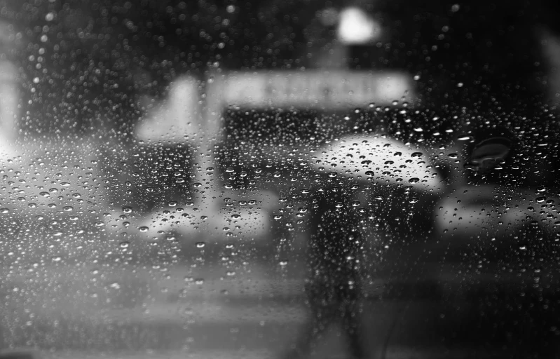 a black and white photo of a car in the rain, a black and white photo, by Daniel Gelon, pexels, realism, bus stop on a rainy day, wet reflections in square eyes, bokeh. i, andrey gordeev