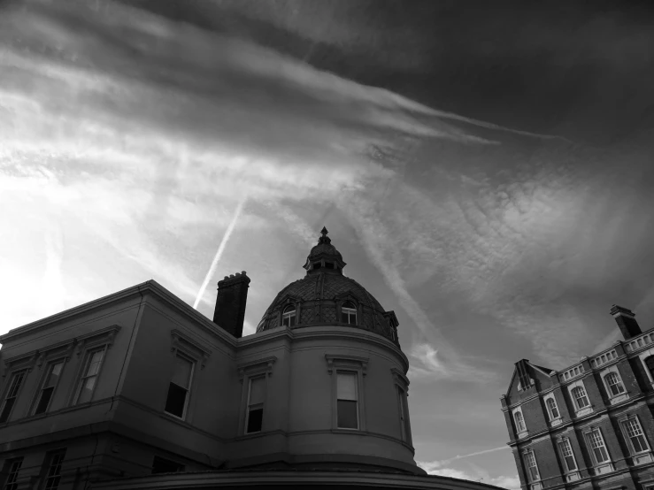 a black and white photo of a building, by Adam Rex, pexels contest winner, baroque, satanistic sky, rounded roof, late afternoon, patches of sky