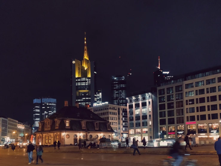 a group of people walking around a city at night, a photo, by Niko Henrichon, pexels contest winner, square, skyline showing, germany, brown
