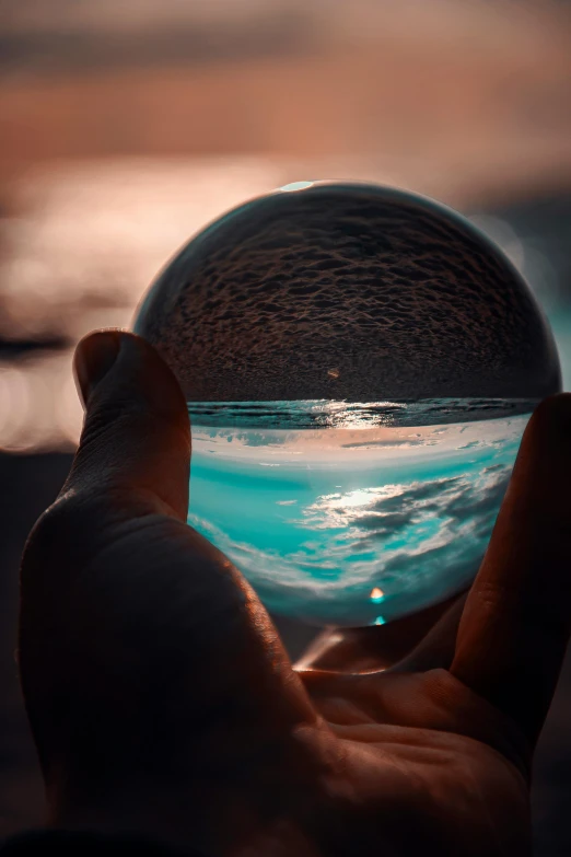 a person holding a glass ball in their hand, inspired by Beeple, unsplash contest winner, magical ocean, 500px, profile pic, ilustration