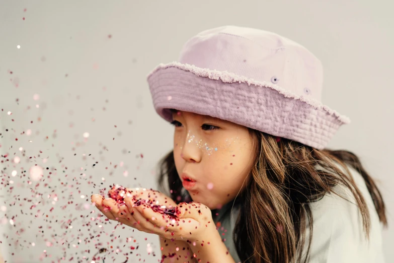 a little girl in a purple hat blowing confetti, trending on pexels, photoshoot for skincare brand, korean girl, wears a destroyed hat, animation