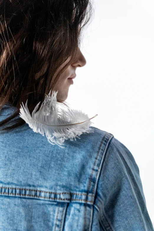 a close up of a person wearing a denim jacket, white feathers, arm around her neck, profile image, product shoot