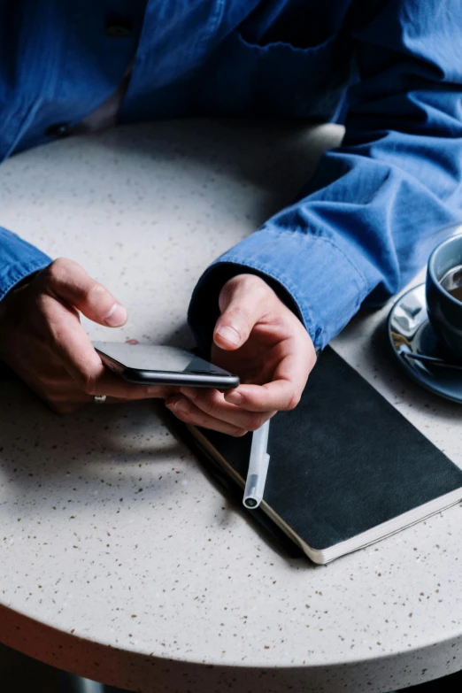 a person sitting at a table using a cell phone, happening, coffee, sitting with wrists together, curated collections, avatar image