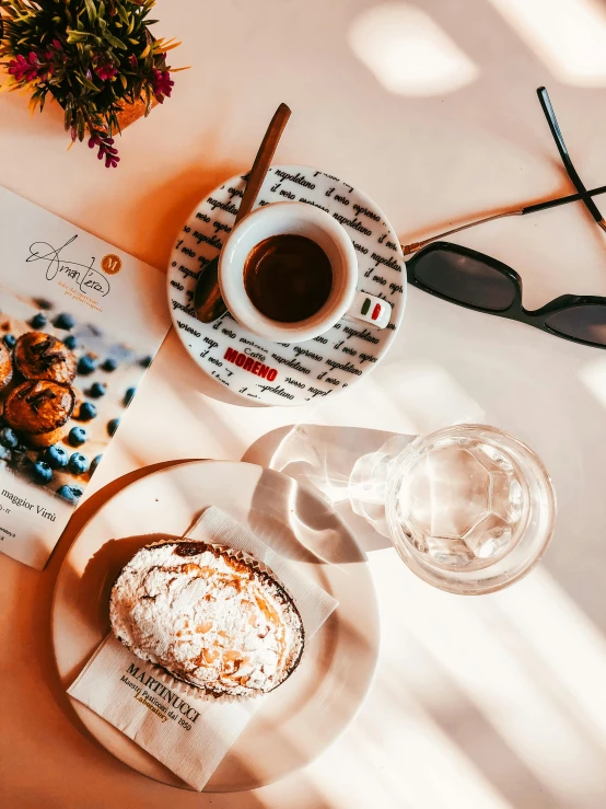 a book sitting on top of a table next to a cup of coffee, pastries, with sunglasses, thumbnail, sparkling