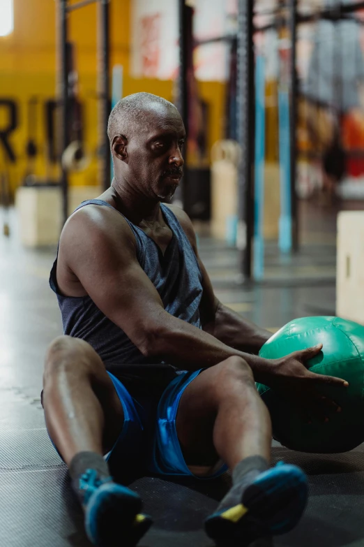 a man sitting on the floor with a medicine ball, lance reddick, multiple stories, athletic build, profile image