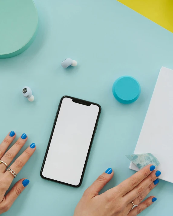 a woman's hands on a table with a phone and ear buds, by Julia Pishtar, hypermodernism, teal palette, photoshoot for skincare brand, primary colors are white, taking a selfie