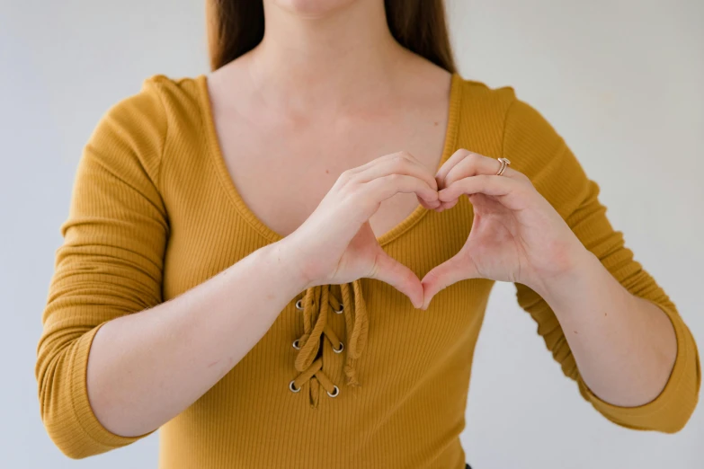 a woman making a heart with her hands, trending on pexels, mustard, profile image, background image, broad shoulders