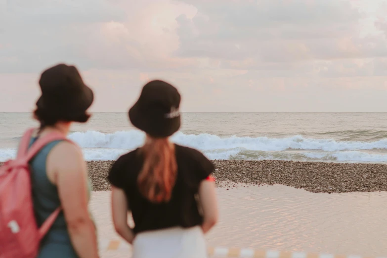 a couple of women standing on top of a sandy beach, pexels contest winner, early evening, profile image, chillwave, looking from behind