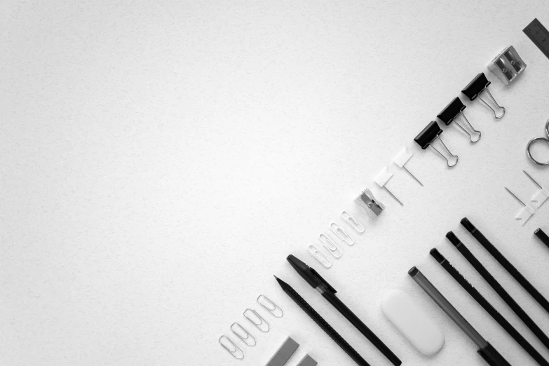 a bunch of pens sitting on top of a table, a black and white photo, by Adam Marczyński, minimalism, clean logo design, background image, knolling, white plastic