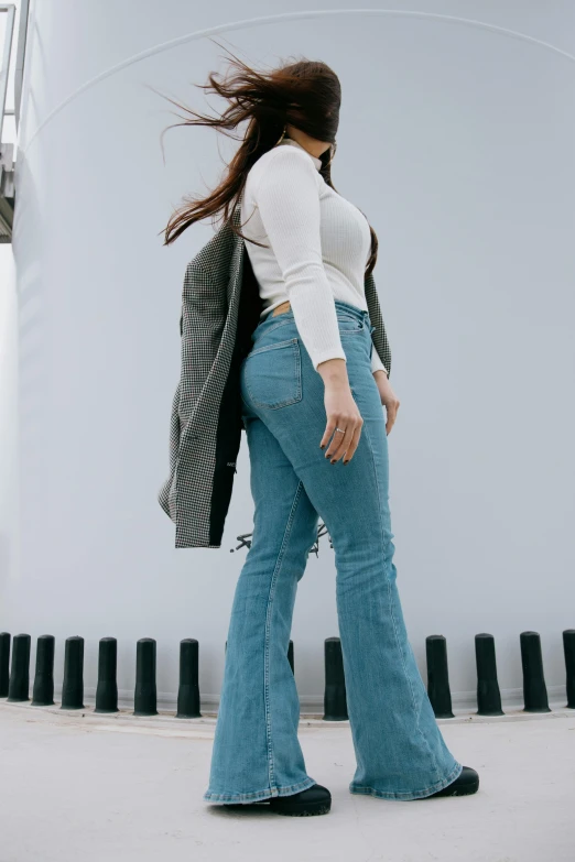 a woman standing in front of a large tank, trending on pexels, jeans and boots, curvy accentuated booty, full body with costume, flares