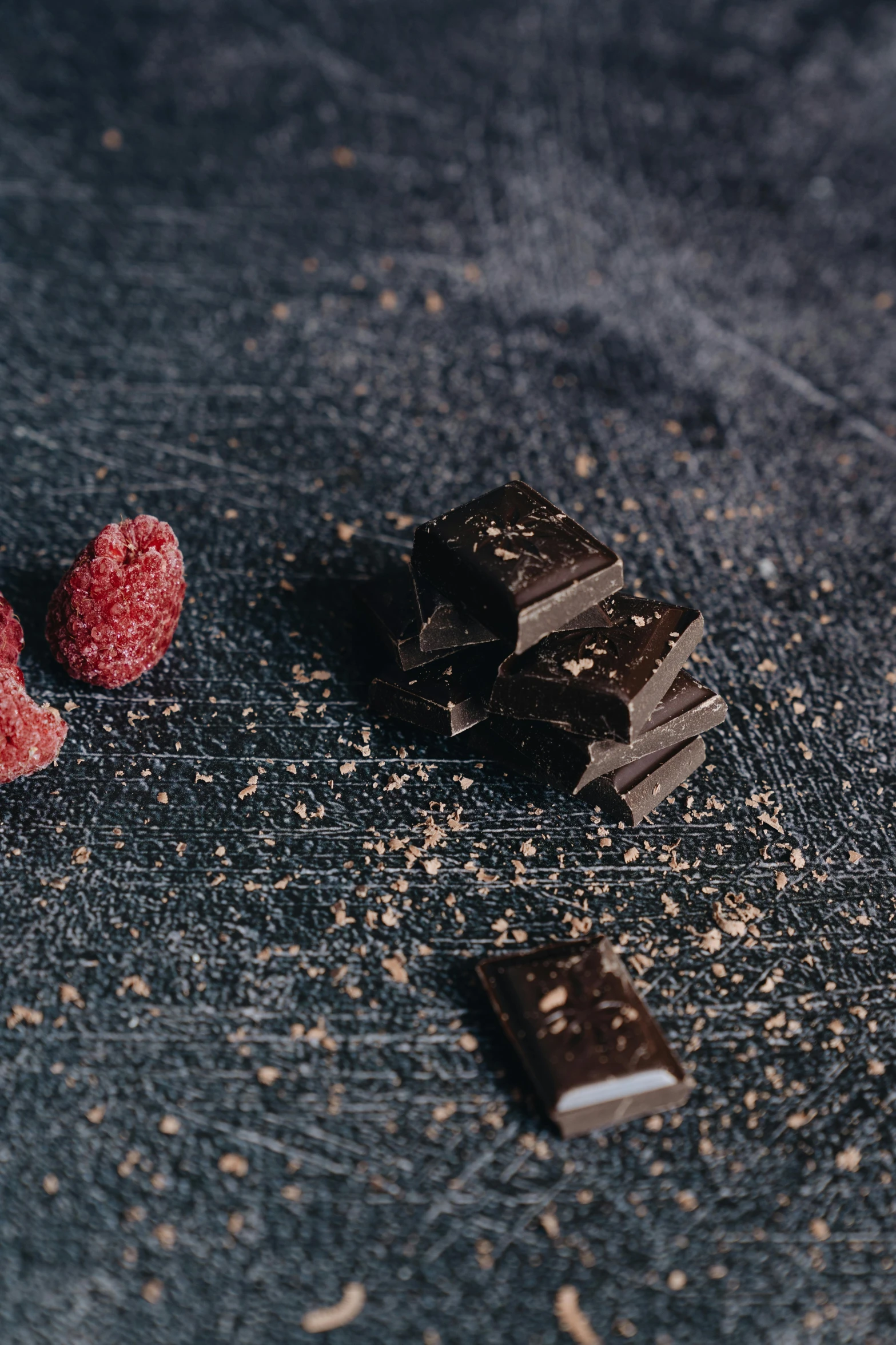 a couple of pieces of chocolate and some raspberries, unsplash, detailed product image, dark. no text, bark for skin, kek