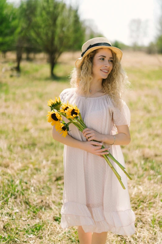 a woman standing in a field holding a bunch of sunflowers, pexels, romanticism, wearing a cute hat, square, julia garner, springtime morning