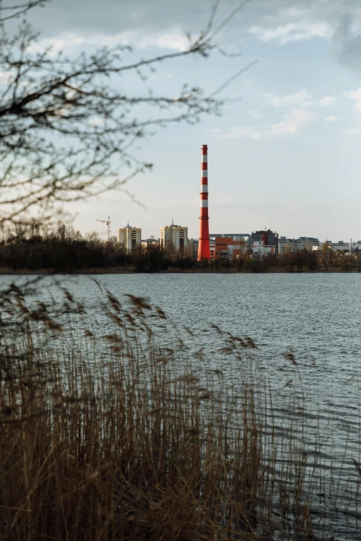 a large body of water with a red tower in the background, by Oskar Lüthy, unsplash, graffiti, power plants, warsaw, 2 0 0 mm telephoto, today\'s featured photograph 4k