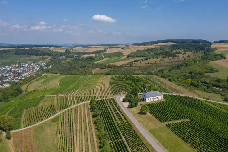 a large field with a church in the middle of it, pexels contest winner, wine, view from the sky, hillside, detmold