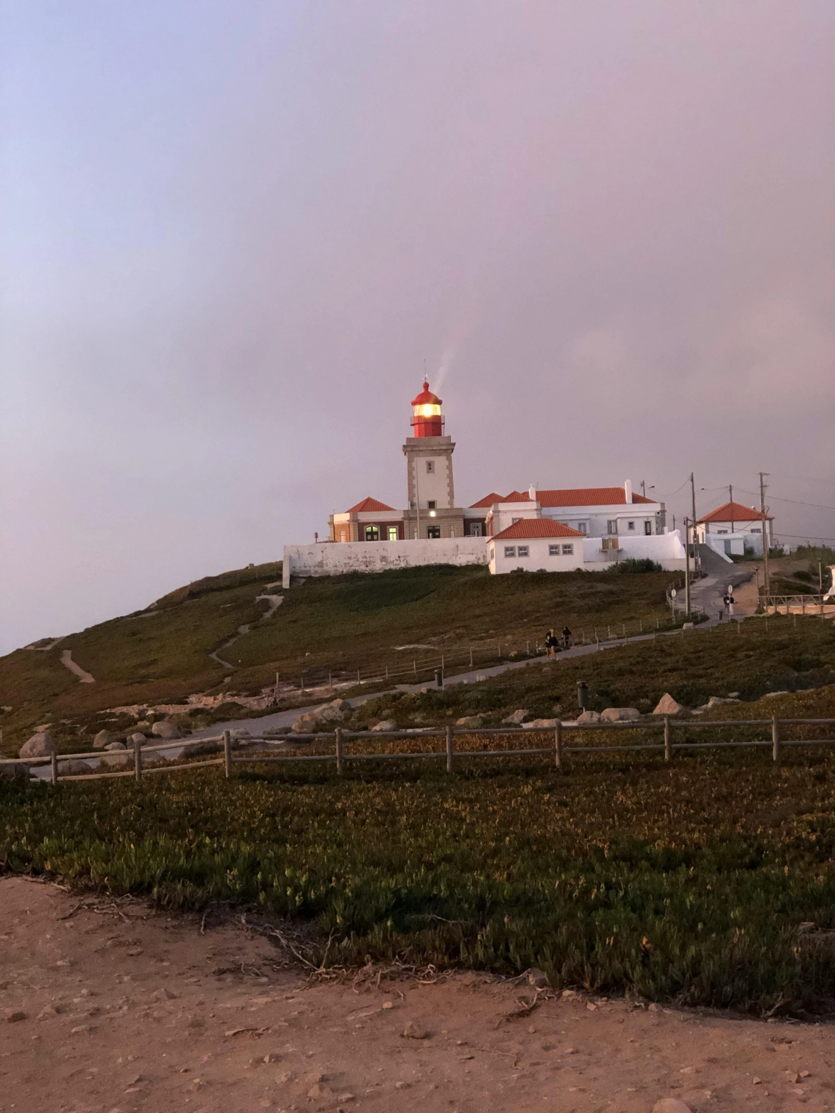 a lighthouse sitting on top of a lush green hillside, a picture, happening, farol da barra, warm glow from the lights, profile image, multiple stories