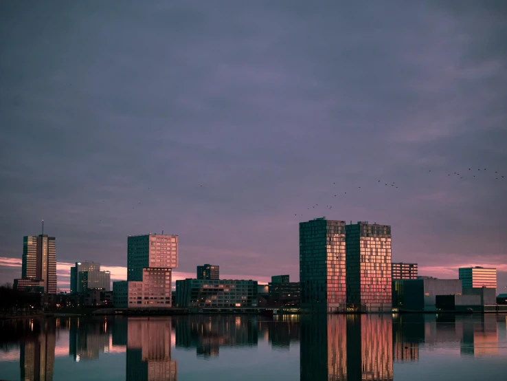 a large body of water surrounded by tall buildings, by Jacob Toorenvliet, pexels contest winner, brutalism, calm evening, helmond, coloured photo, 1 4 9 3