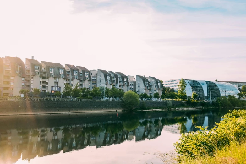 a body of water with buildings in the background, inspired by Washington Allston, unsplash, happening, rennes - le - chateau, frank gehry, riverside, esher