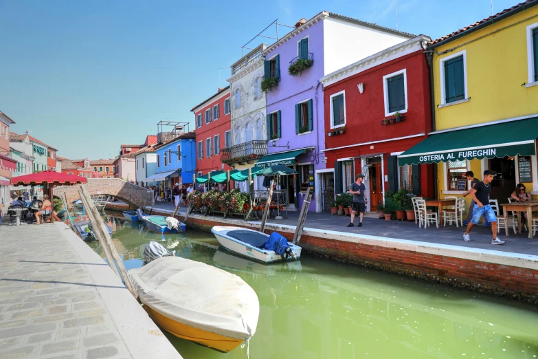 a group of boats sitting on the side of a river, a photo, inspired by Quirizio di Giovanni da Murano, pexels contest winner, colorful house, primary colors are white, photorealistic streetscape, pastel colored